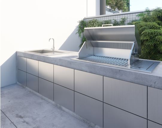 Drop-in BBQ grill in stainless steel with the hood open, set into a concrete outdoor kitchen counter beside a sink